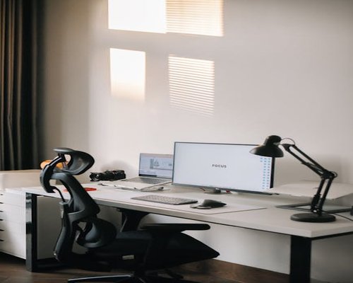 A well-lit home office desk with an ergonomic chair